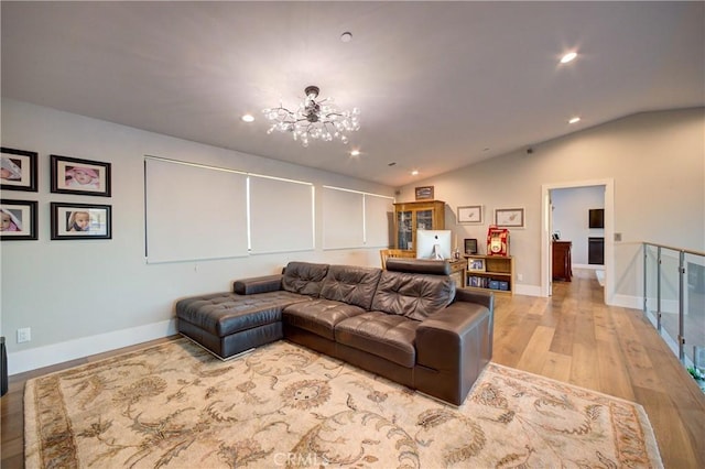 living room featuring vaulted ceiling, a chandelier, and light wood-type flooring