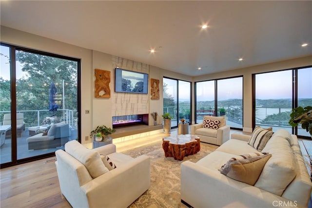 living room with a large fireplace, a wealth of natural light, and light wood-type flooring