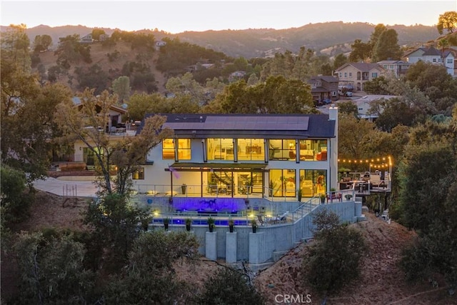 back house at dusk featuring a balcony and a mountain view