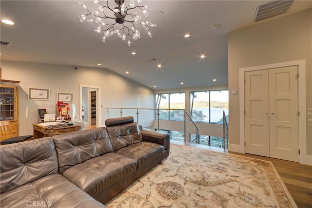 living room with an inviting chandelier, wood-type flooring, and vaulted ceiling