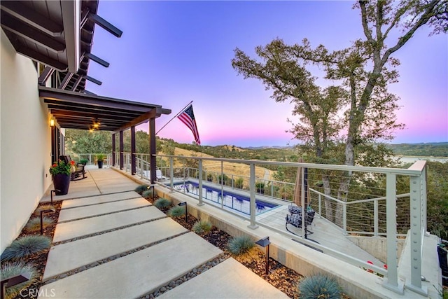 pool at dusk featuring a patio