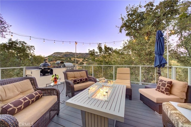 deck at dusk with a mountain view and an outdoor living space with a fire pit