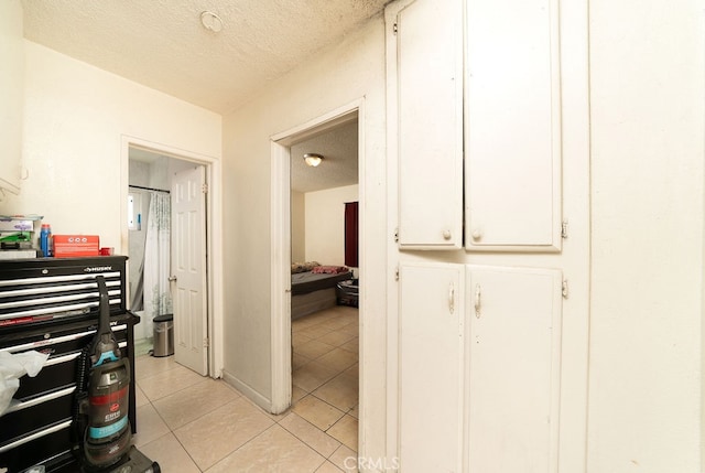 corridor with light tile patterned floors and a textured ceiling