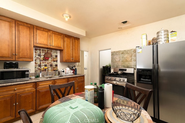 kitchen with stainless steel appliances, backsplash, sink, and light tile patterned floors