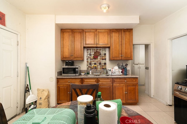 kitchen featuring stove, sink, and light tile patterned floors