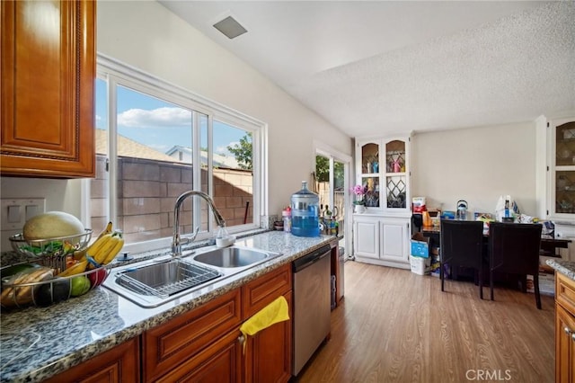 kitchen featuring light stone countertops, stainless steel dishwasher, a textured ceiling, sink, and light hardwood / wood-style flooring