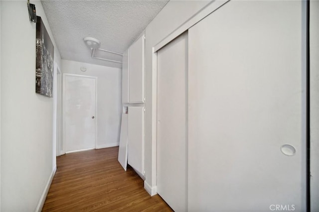 corridor featuring wood-type flooring and a textured ceiling