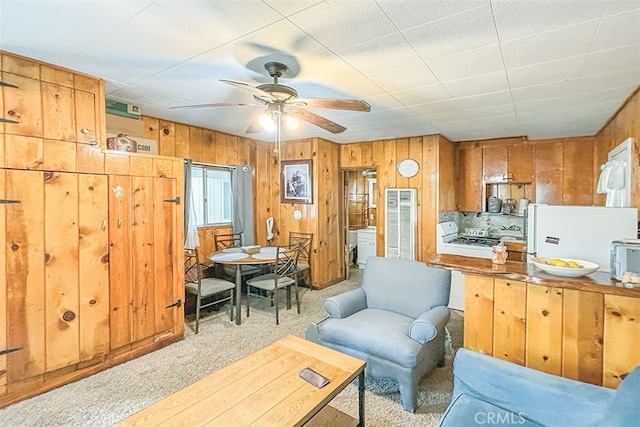 living room with wooden walls, light carpet, and ceiling fan