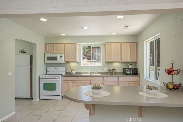 kitchen featuring white appliances, light brown cabinetry, sink, and plenty of natural light