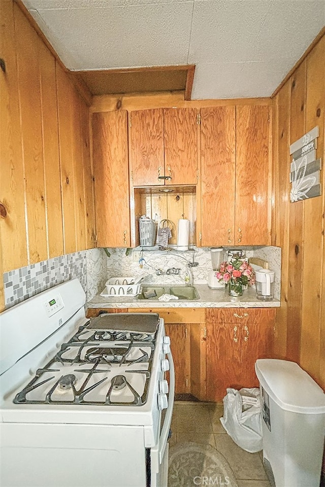 kitchen featuring decorative backsplash, gas range gas stove, tile patterned floors, and a textured ceiling