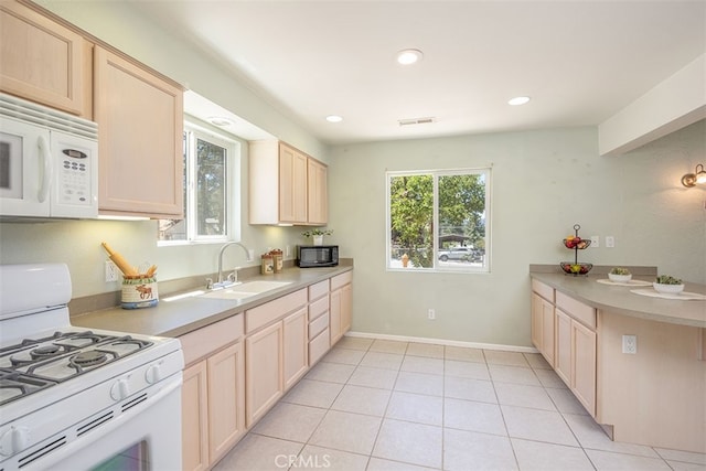 kitchen with light tile patterned floors, sink, light brown cabinetry, and white appliances