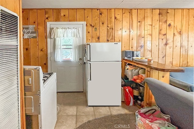 kitchen with white appliances, wood walls, and light tile patterned floors