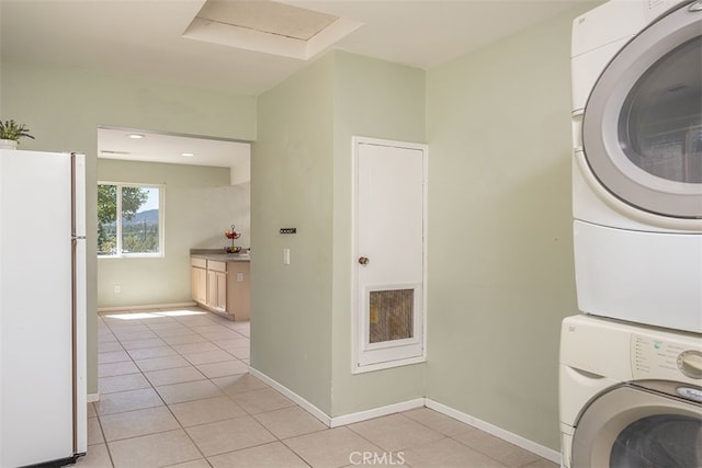 laundry area with light tile patterned floors and stacked washer and dryer