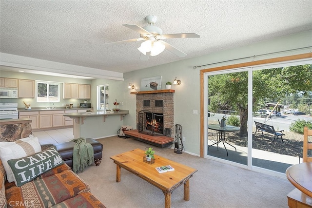 living room with light carpet, ceiling fan, a textured ceiling, a fireplace, and sink