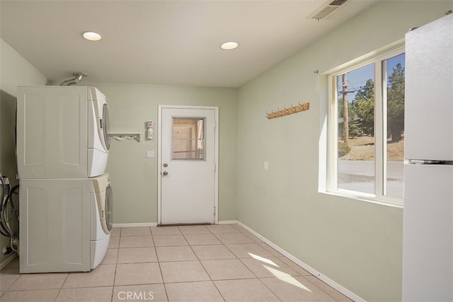 laundry area with stacked washing maching and dryer and light tile patterned floors