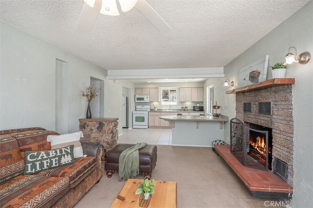 living room featuring light carpet, a textured ceiling, ceiling fan, and a brick fireplace