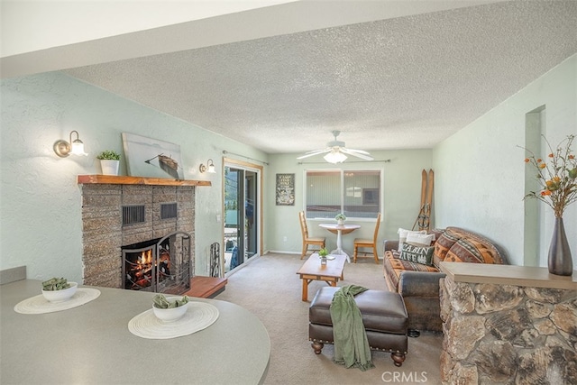 living room featuring light colored carpet, ceiling fan, a textured ceiling, and a fireplace