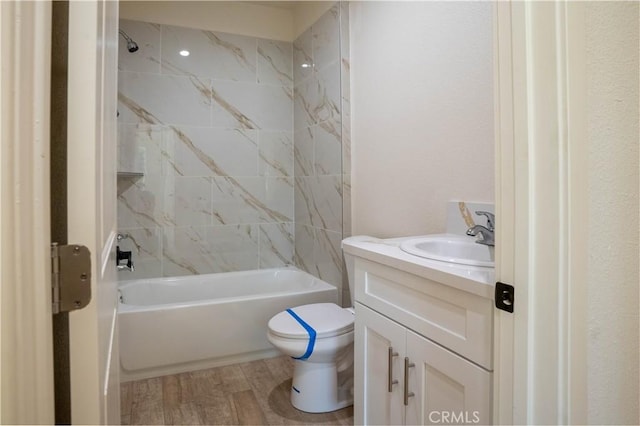 full bathroom with tiled shower / bath combo, vanity, hardwood / wood-style flooring, and toilet