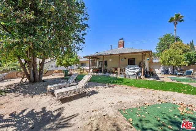 rear view of property with a patio and a pool