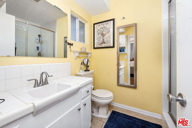 bathroom featuring tasteful backsplash, a shower with shower door, vanity, toilet, and tile patterned floors