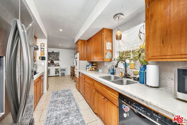 kitchen featuring pendant lighting, sink, stainless steel refrigerator, black dishwasher, and decorative backsplash