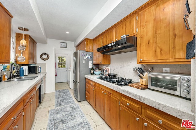 kitchen with a textured ceiling, sink, hanging light fixtures, appliances with stainless steel finishes, and light tile patterned floors