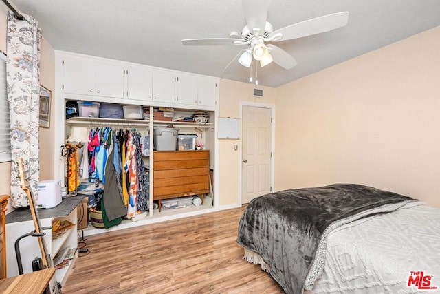 bedroom with light wood-type flooring, ceiling fan, and a closet