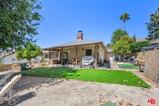 back of house with ceiling fan, a lawn, and a patio