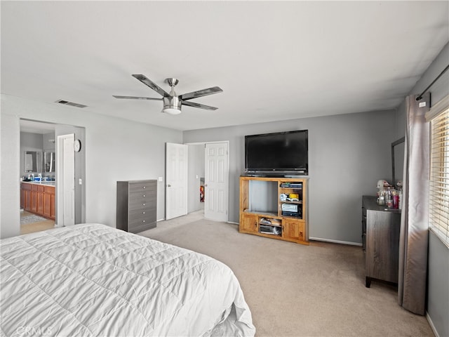 bedroom featuring light carpet, ceiling fan, and ensuite bathroom