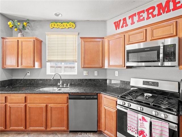 kitchen with light tile patterned flooring, appliances with stainless steel finishes, sink, and dark stone counters