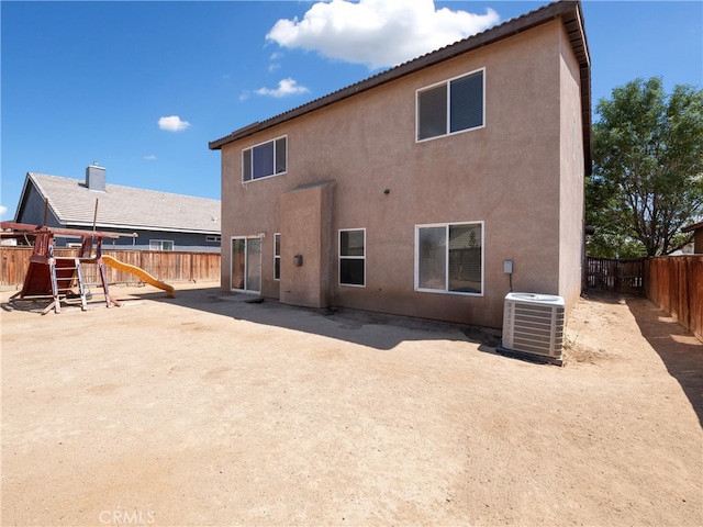 rear view of property featuring a playground, cooling unit, and a patio area