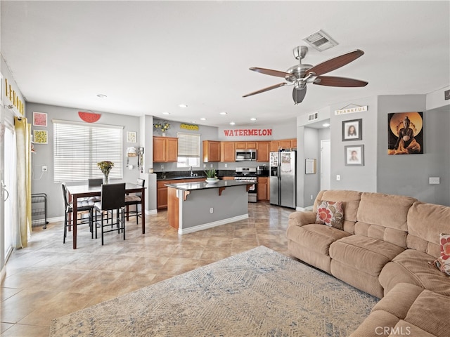 tiled living room featuring ceiling fan and sink