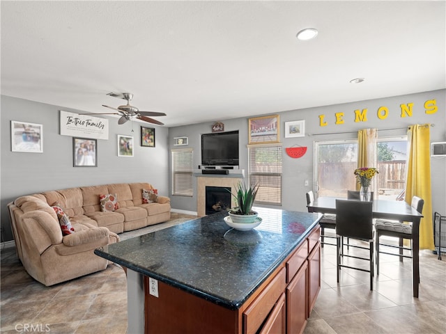 kitchen featuring ceiling fan, a fireplace, light tile patterned floors, and a center island