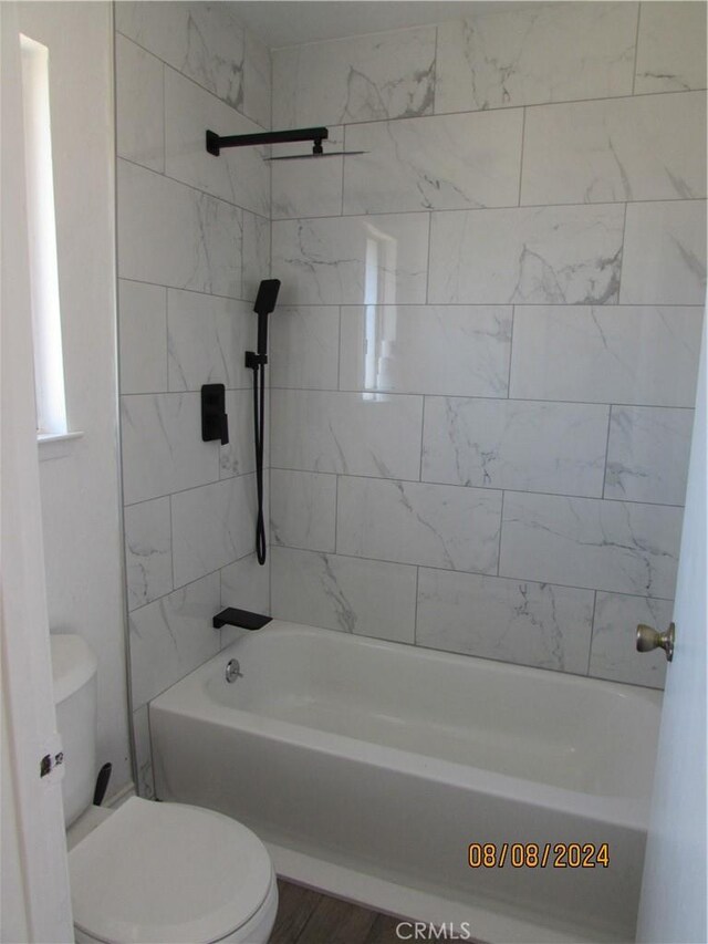 bathroom featuring tiled shower / bath combo and toilet