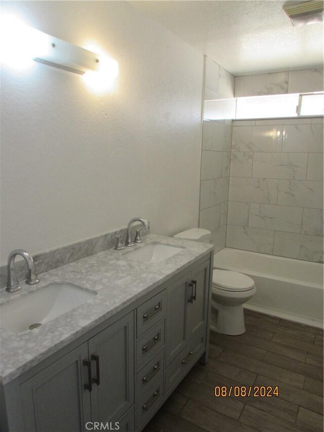 full bathroom featuring vanity, wood-type flooring, tiled shower / bath combo, and toilet