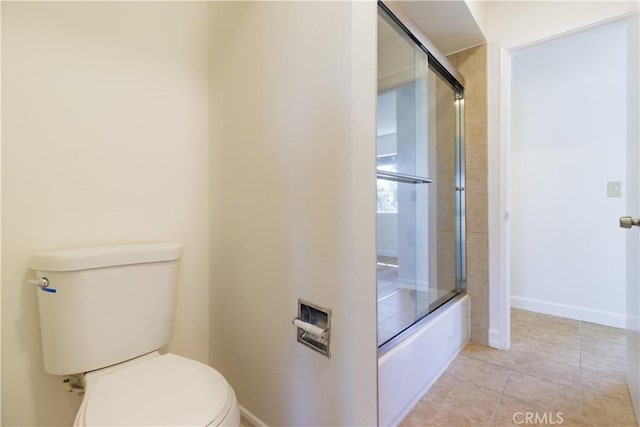 bathroom featuring toilet, combined bath / shower with glass door, and tile patterned flooring