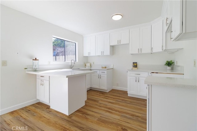 kitchen featuring light wood-type flooring, white cabinetry, and sink