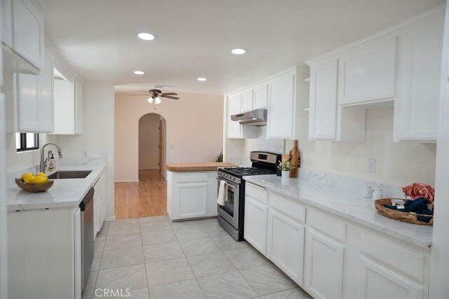 kitchen with appliances with stainless steel finishes, white cabinetry, sink, light tile patterned floors, and ceiling fan