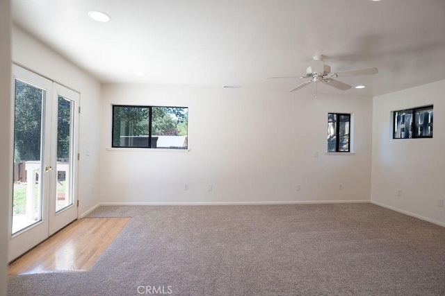 spare room with ceiling fan, plenty of natural light, and light carpet