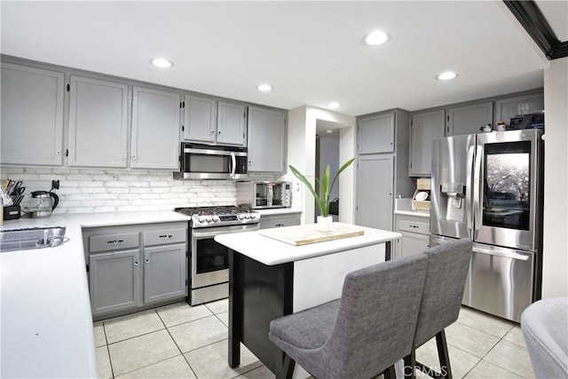 kitchen featuring tasteful backsplash, gray cabinetry, stainless steel appliances, and light tile patterned flooring