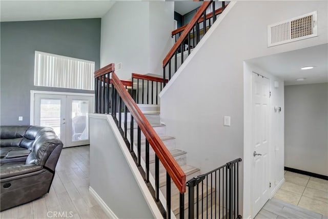 staircase featuring french doors, high vaulted ceiling, and hardwood / wood-style floors