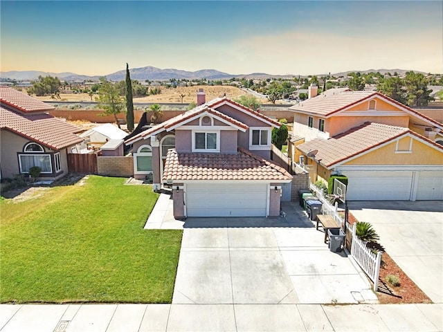 view of front property featuring a garage, a mountain view, and a yard