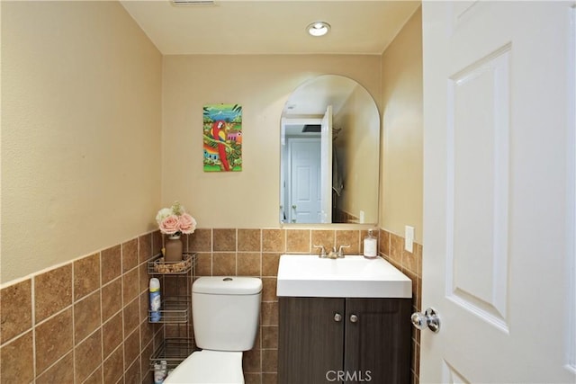 bathroom featuring vanity, tile walls, and toilet