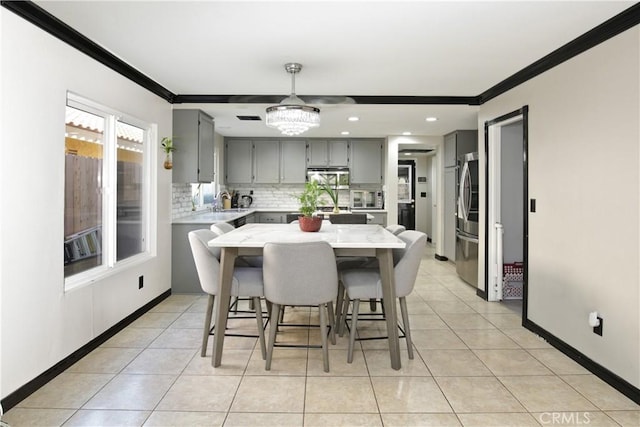 tiled dining space with an inviting chandelier, sink, and ornamental molding