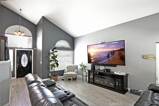 living room with a chandelier, a healthy amount of sunlight, light hardwood / wood-style floors, and high vaulted ceiling