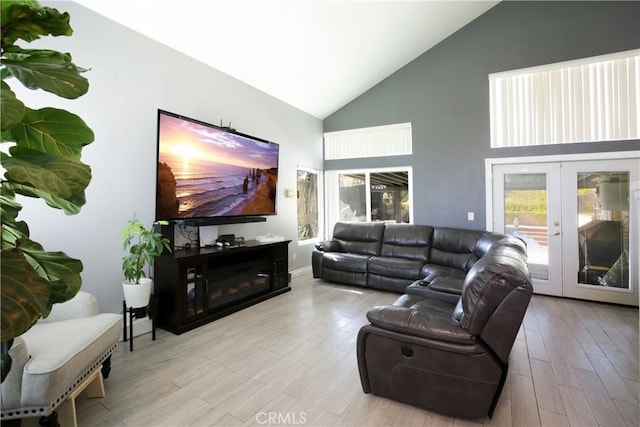 living room featuring high vaulted ceiling, french doors, and light wood-type flooring