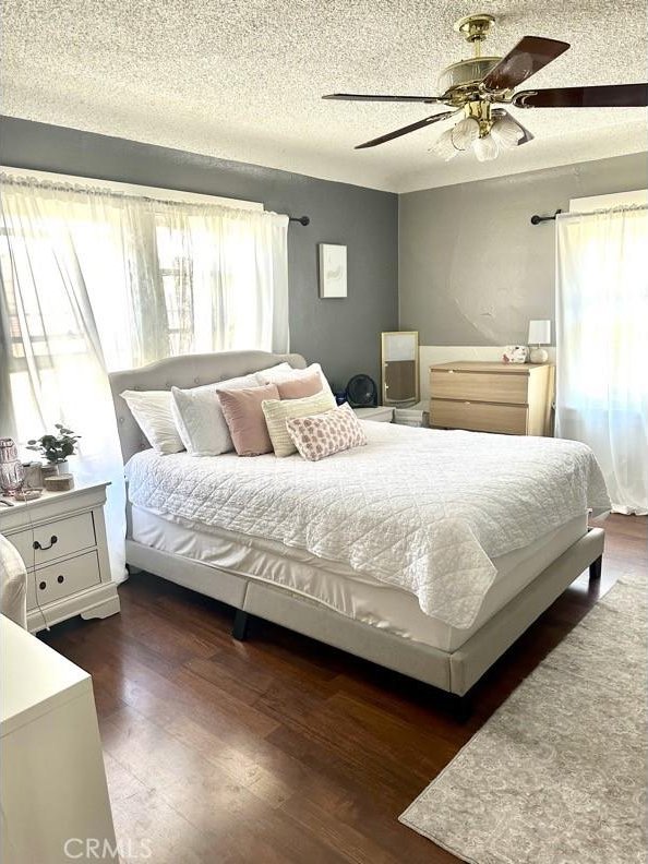 bedroom featuring a textured ceiling, ceiling fan, and dark hardwood / wood-style floors