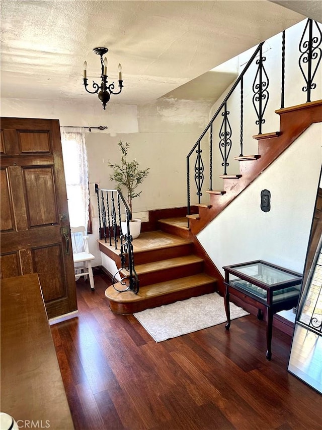 foyer entrance featuring dark hardwood / wood-style flooring, a textured ceiling, and a notable chandelier