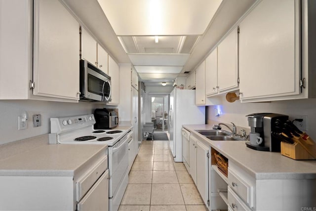 kitchen with light tile patterned floors, sink, white appliances, and white cabinetry