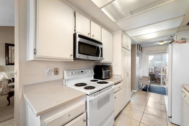 kitchen featuring white appliances, light tile patterned floors, and white cabinets